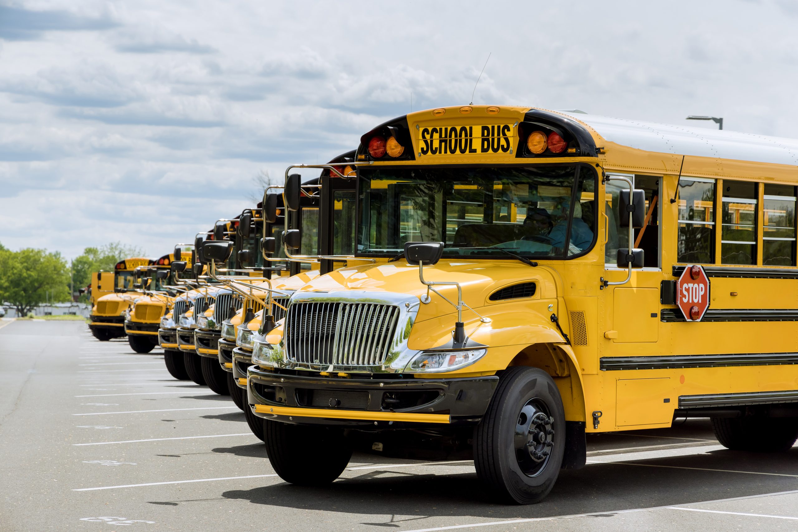 view yellow school buses parked near high school scaled